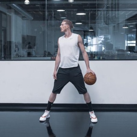 Photo of Kyle Singler holding a basketball by wearing white T-shirt.